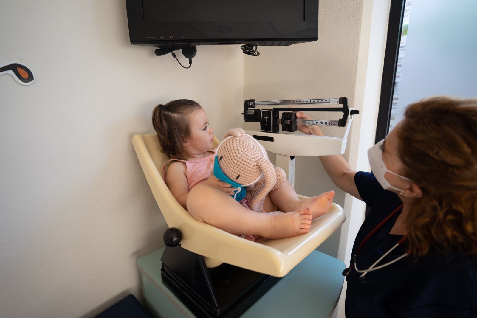 A clinician measuring a child's height against a wall chart